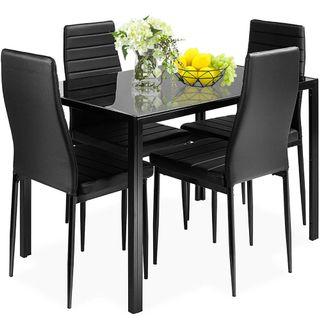 Black dining table with four matching chairs, glass top, and metal frame